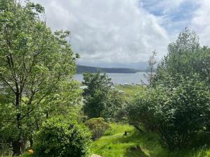 a view of a field with trees and a body of water at Hawthorn Cottage in Uig