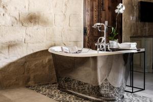 a bathroom with a tub with a book on it at Cesca's Boutique Hotel in Xlendi