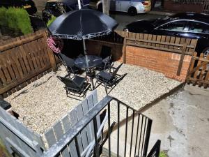 a patio with a table and chairs and an umbrella at *11BR* Setup for your most amazing relaxed stay + Free Parking + Free Fast WiFi * in Beeston