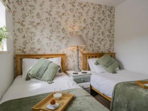 a bedroom with two beds and a table with a tray at Columbine Cottage in Ambleside