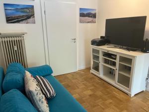 a living room with a blue couch and a television at Apartment Wendelsteinblick - Wohnen auf Zeit - Homeoffice - Balkon mit Bergblick- buchbar ab 28 Nächte in Schliersee