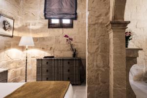a room with a dresser and a lamp and a stone wall at Cesca's Boutique Hotel in Xlendi