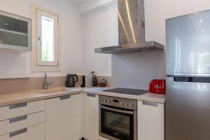 a kitchen with white cabinets and a stainless steel refrigerator at NAMASTE Boutique Apartments Mykonos in Tourlos