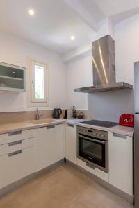 a kitchen with white cabinets and a stove top oven at NAMASTE Boutique Apartments Mykonos in Tourlos