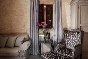a living room with a chair and a window at Cesca's Boutique Hotel in Xlendi