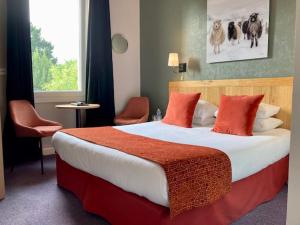 ナントにあるHôtel Coeur De Loireの大きなベッド(赤い枕付)が備わる客室です。