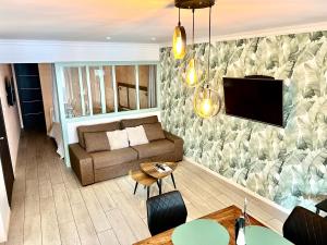 een woonkamer met een bank en een tv aan de muur bij Plage à 50m Appartement Rêves tranquilles Villa Les Bains de Mers in Mers-les-Bains