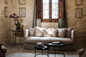 a living room with a couch and two tables at Cesca's Boutique Hotel in Xlendi
