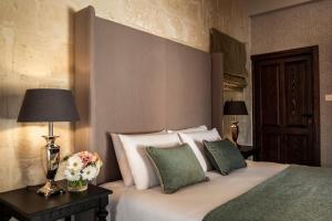 a bedroom with a bed with white sheets and green pillows at Cesca's Boutique Hotel in Xlendi