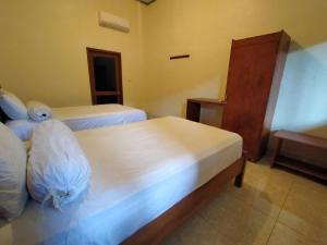a hotel room with two beds and a dresser at Sari Laut in Gili Meno