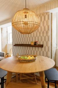 a basket of fruit on a wooden table with a light fixture at Green Apartment Foz in Porto