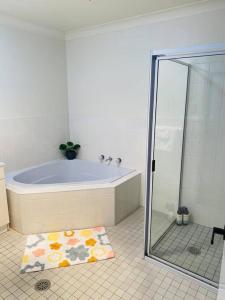a bathroom with a tub and a shower and a rug at Family Favourite, Spacious 2 Bedroom Unit in Young