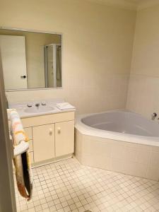 a bathroom with a tub and a sink and a mirror at Family Favourite, Spacious 2 Bedroom Unit in Young