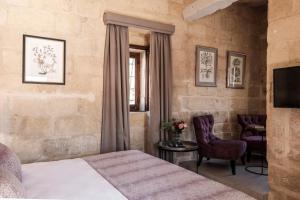 a bedroom with a bed and a chair and a television at Cesca's Boutique Hotel in Xlendi