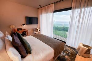 a bedroom with a bed and a large window at LOISIUM Wine & Spa Hotel Champagne in Mutigny