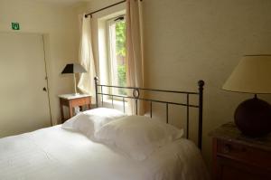 ein Schlafzimmer mit einem Bett mit weißen Laken und einem Fenster in der Unterkunft B&B De Hulst in Izegem
