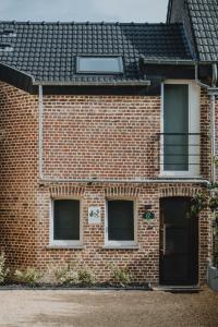 a brick building with three windows and a roof at Le Paradis d'Henri in Hannut