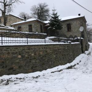 a stone wall in the snow with a house at Vila Korcari Dardhe in Dardhë +2 photos