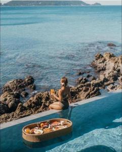 a woman sitting in the ocean with a tray of food at patong sunset villa Phuket in Patong Beach