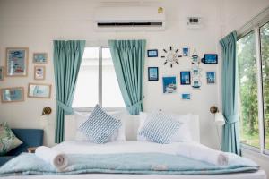 a bedroom with a bed with blue curtains and a window at Thirty Tree Garden House in Chumphon