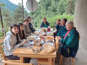 a group of people sitting at a table eating food at Guesthouse Gama in Khevsureti in Roshka