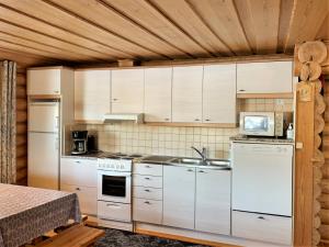a kitchen with white appliances and wooden ceilings at Lappalaisen lomamökit Lepola in Puumala