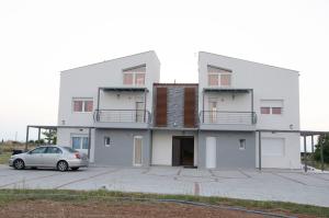 a white building with a car parked in front of it at Garden's Sunset Αvra in Néa Michanióna