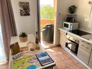a kitchen with a table with a bottle of wine on it at Coeur de Fréjus, L'AMPHITHÉÂTRE, appartement 3 pièces climatisé, terrasse, barbecue, piscine & parking in Fréjus