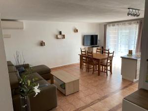 ein Wohnzimmer mit einem Sofa, einem Tisch und Stühlen in der Unterkunft Coeur de Fréjus, L'AMPHITHÉÂTRE, appartement 3 pièces climatisé, terrasse, barbecue, piscine & parking in Fréjus