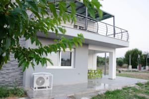 a white house with a balcony on top of it at Garden's Sunset Αvra in Néa Michanióna +10 photos