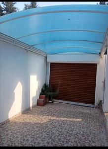 a garage with a blue roof on top of it at Maison koukou in Boumhel El Bassatine
