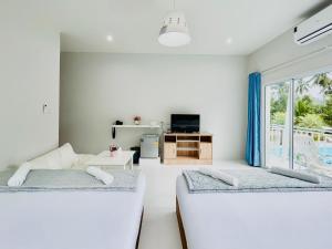 een witte kamer met 2 bedden en een raam bij Thirty Tree Garden House in Chumphon