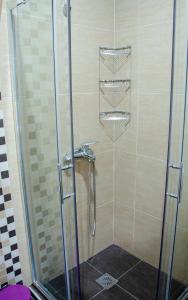 a shower stall with a glass door and a shower at Garden's Sunset Αvra in Néa Michanióna