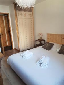 a bedroom with a large white bed with towels on it at bel appartement , son jardin et le lac in Chamonix-Mont-Blanc