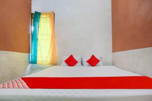 1 cama con 2 almohadas rojas en una habitación en OYO 91051 Penginapan Pondok Ratu 354 en Pontianak