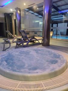 uma banheira de hidromassagem num quarto com cadeiras e uma piscina em ARVA Spa París em León
