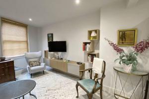 a living room with a tv and chairs and a table at Charming 2-Bed Apt with 2 bathtub central London in London