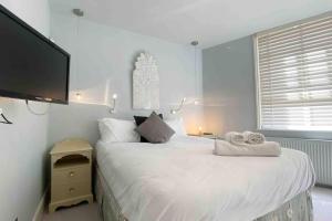 a bedroom with a large white bed with towels on it at Charming 2-Bed Apt with 2 bathtub central London in London