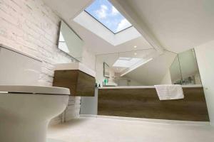 an attic bathroom with a toilet and a skylight at Charming 2-Bed Apt with 2 bathtub central London in London