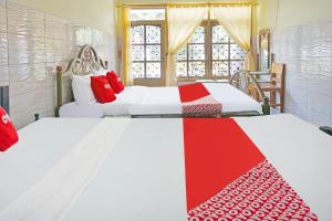 a bedroom with two beds with red and white blankets at OYO 91411 Putih Mulia Homestay Syariah in Lumajang
