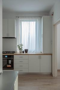 a kitchen with white cabinets and a window at Solomon Apartments Ap 3 in Sângeorgiu de Mureș