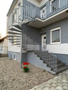 a house with stairs and red flowers in front of it at ubytovanie OPÁL in Štúrovo