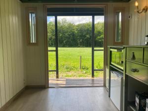 an open door to a kitchen with a view of a field at Tiny house, pipowagen onder de kastanje in Aalten
