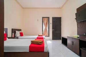 a hotel room with two beds and a television at RedDoorz @ Wisma Pangrango in Palangkaraya