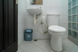 a bathroom with a toilet and a sink and a trash can at RedDoorz @ Wisma Pangrango in Palangkaraya