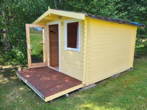 un capannone giallo con una terrazza in legno in un cortile di Lõunamatkad a Kiidjärve