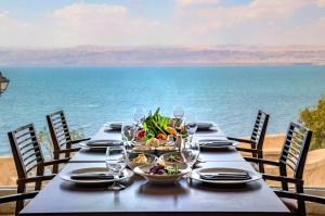 a table with food and wine glasses and the ocean at Crowne Plaza Jordan Dead Sea Resort & Spa, an IHG Hotel in Sowayma