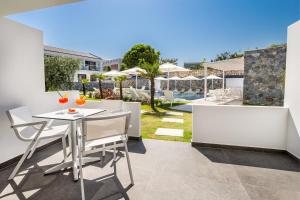 een patio met een tafel en stoelen en een zwembad bij Epicentrum Suites Fresh in Limenaria