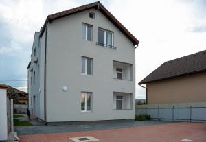 a white building with a brown roof at Solomon Apartments Ap 3 in Sîngeorgiu de Mureş