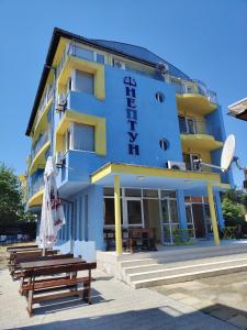 a blue and yellow building with benches in front of it at Hotel Neptun - Lozenets in Lozenets
